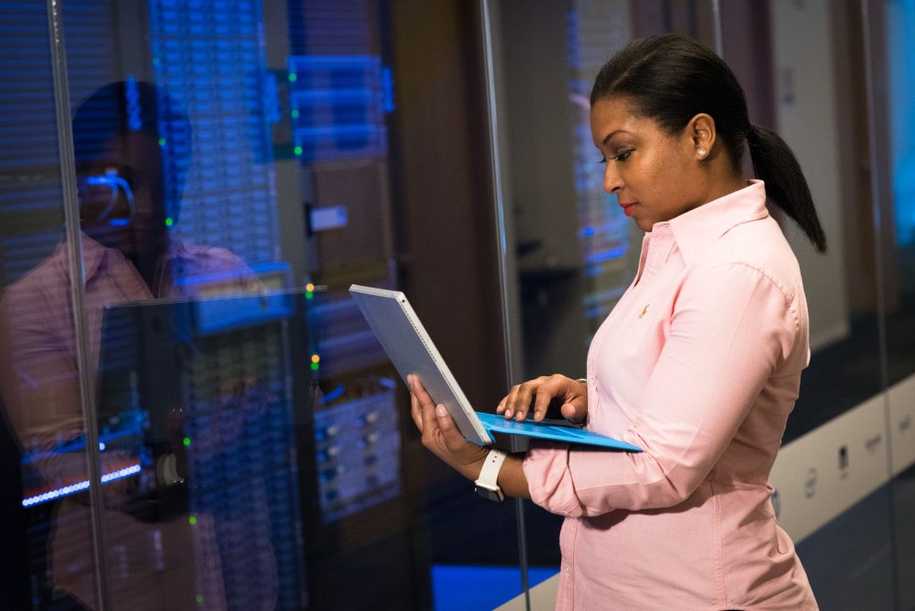 Software engineer working on a laptop beside server infrastructure