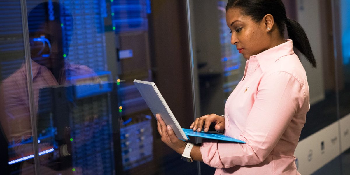 Software engineer working on a laptop beside server infrastructure