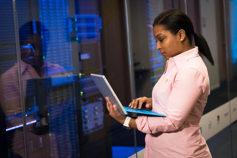 Software engineer working on a laptop beside server infrastructure