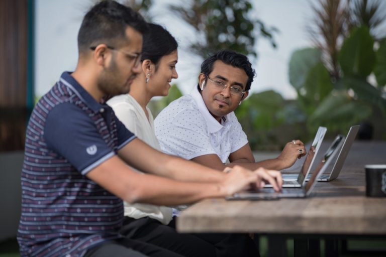 Engineers reviewing connected systems together on laptops