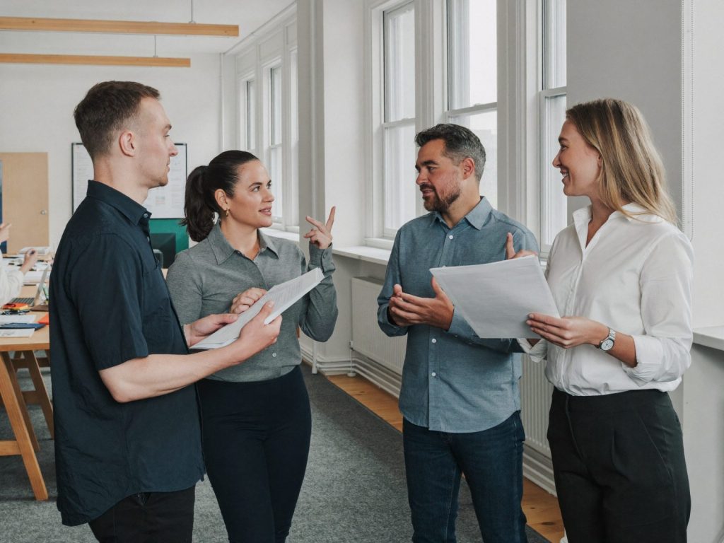 Four colleagues standing in an office discussing a process together