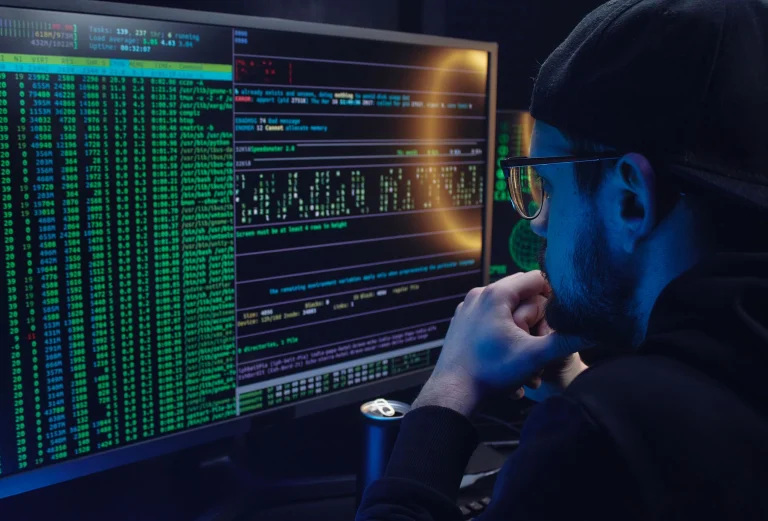 Engineer studying programming information across two monitors